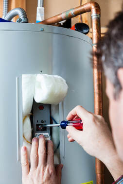 A picture of a man adjusting a hot water heater in Erie Pa